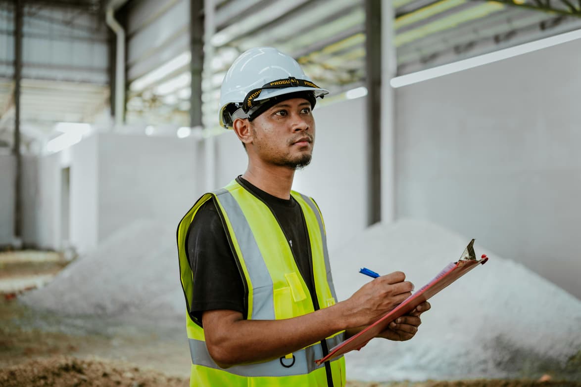 A worker in a hard hat and hi-vis vest on an industrial site